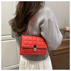 Close-up of bright red quilted crossbody bag with silver chain strap and metal lock