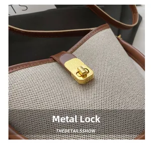Close-up of golden rectangular twist lock on beige canvas and brown leather handbag