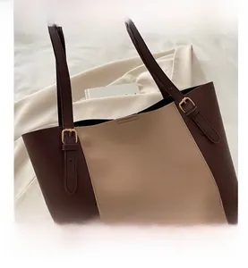 Close-up of contrast-color leather tote bag with brand logo and gold hardware details