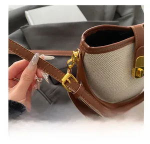 Detail of adjustable leather shoulder strap and gold buckle on a canvas bucket bag