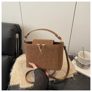 Detail of leopard print brown leather bag with golden V-shaped buckle and hand strap