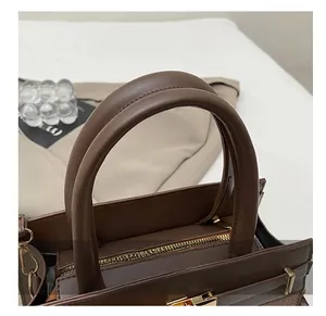 Détails d'un sac à main en cuir marron foncé avec coutures et garnitures dorées