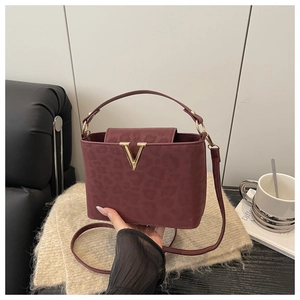 Detail of burgundy leopard embossed tote bag with gold V clasp on a knit fabric