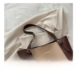 Detail of color-block tote bag featuring adjustable buckle straps and golden logo