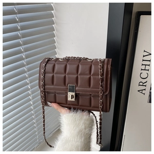 Detail of dark brown quilted crossbody bag with silver twist lock and metal chain strap