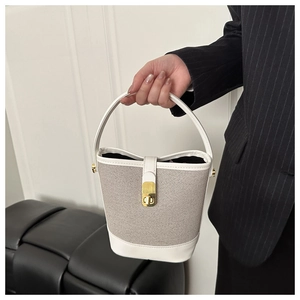 Detail of white leather and grey woven fabric bucket bag with a gold twist-lock closure