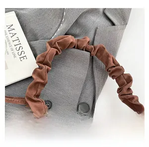 Detail of brown pleated handbag showing suede texture and unique cloud-shaped handle