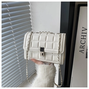 Close-up of white quilted crossbody bag with silver chain strap and metal lock detail
