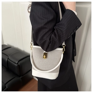 Detail of white leather and beige woven bucket bag with golden buckle on a model