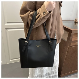 Detail of adjustable gold buckle on a black leather tote shoulder bag strap