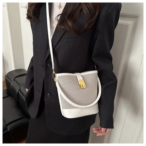 On-body shot of a woven bucket bag with leather trim and gold twist-lock closure