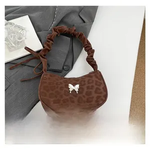 Detail of leopard print handbag featuring silver butterfly buckle and ruched handle