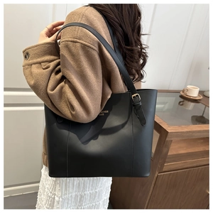 Detail of minimalist black tote bag with gold logo and adjustable shoulder strap