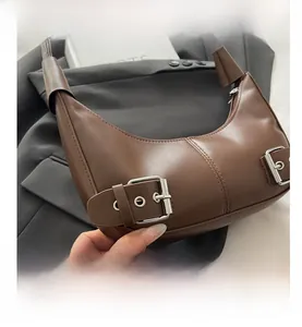 Detail shot of brown crescent underarm bag with metal buckles and vertical stitching