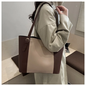Detail of a large leather tote bag with color-block design and gold adjustable buckle