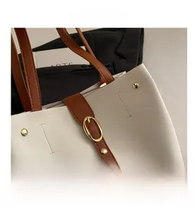 Détail du cabas bicolore avec anses en cuir marron et boucle en métal doré