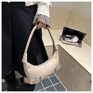Detail of beige crescent hobo bag with silver buckle straps and sleek leather texture