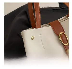 Détail du cabas en similicuir crème avec lanières brunes, boucles dorées et coutures soignées