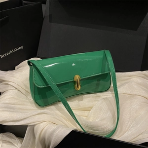 Borsa baguette verde lucida minimalista con fibbia dorata su una scatola nera elegante