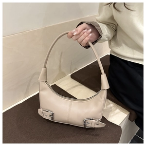 Detail of cream crescent bag featuring dual adjustable buckle straps and smooth leather texture