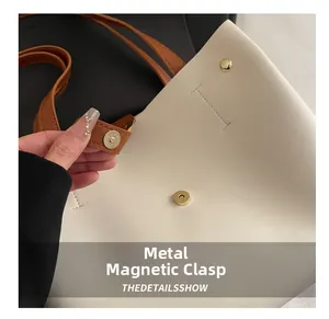 Vue détaillée du fermoir magnétique doré sur un sac cabas en cuir crème élégant