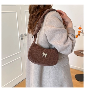 Detailed view of brown leopard print hobo bag with silver butterfly charm on shoulder