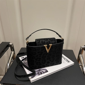 Black leopard print crossbody bag with gold V-buckle accent on minimalist leather