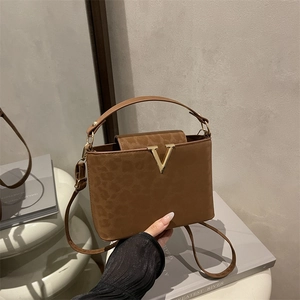 Caramel brown handbag with leopard texture and gold V-logo, shown in a stylish setting