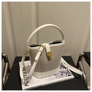 Detail of the bucket bag showing contrast stitching, gold clasp and woven texture