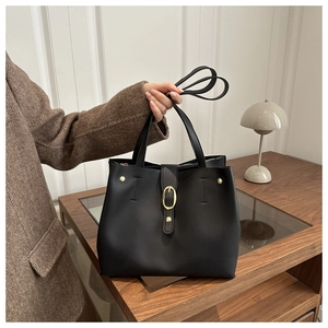 Gros plan du sac cabas à rivets noir avec boucle dorée sur un bureau minimaliste