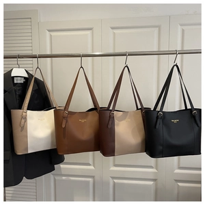 Close-up of four large faux leather tote bags in various colors on a metal hanger