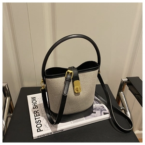 Detail of canvas and black leather bucket bag with gold hardware and rotary lock