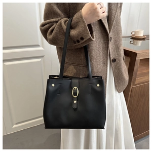 Détail d'un sac cabas en cuir noir avec ferrures dorées porté par un mannequin chic