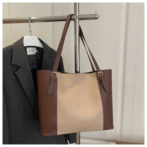Detail of minimalist two-tone tote bag with adjustable straps and metallic logo