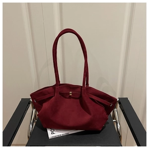 Detailed close-up of dark burgundy suede tote bag with elegant metallic clasp and long handles