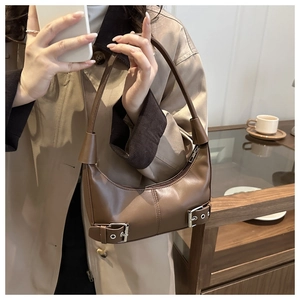 Close-up of brown vintage leather crescent bag featuring dual silver buckle details