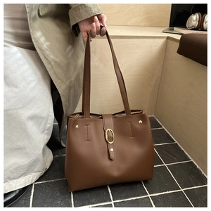 Détail d'un grand sac fourre-tout caramel avec boucle dorée ovale et rivets en décor moderne