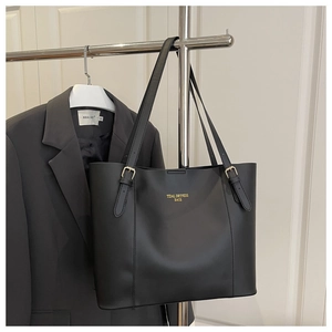 Detail of adjustable strap and gold logo on a professional matte black tote bag