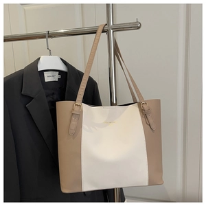 Detail of minimalist tote bag with two-tone design and adjustable gold buckles for commuting