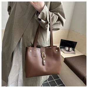 Détail d'un grand sac cabas en cuir marron avec boucle dorée et longues bandoulières