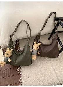 Detail of army green and coffee suede tote bags with cute bunny charms on a soft rug