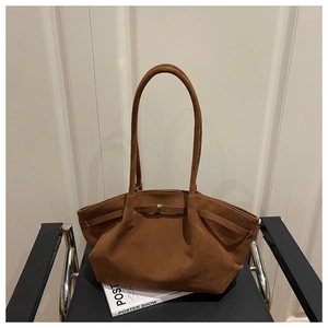 Detailed view of brown suede tote bag with long shoulder straps on a minimalist chair