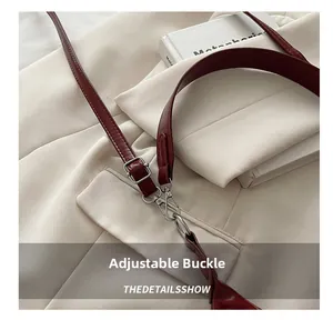 Close-up of adjustable wine red leather shoulder strap with silver buckle and lobster clasp