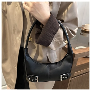 Close-up of black leather hobo bag with dual silver buckles shown in a cafe setting