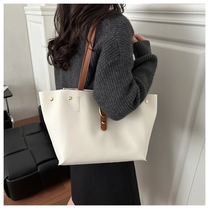 Détail du sac cabas en cuir blanc avec rivets dorés et bandoulière en cuir marron