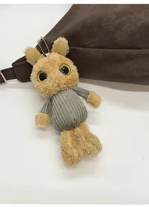Close-up of cute plush charm with corduroy sweater hanging on a leather handbag