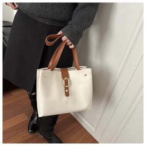 Détail du cabas crème avec anses marron et boucle en métal doré pour un style chic