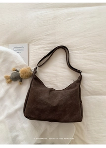Detail of dark brown matte hobo bag with wide shoulder strap and cute bear charm