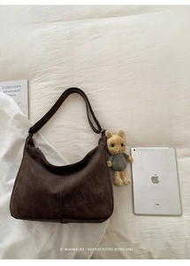 Detail of dark brown faux suede hobo bag with retro texture and plush rabbit charm