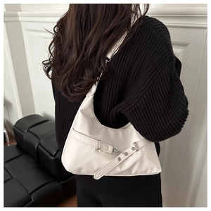 White glossy leather underarm bag worn over a black sweater by a model, back view